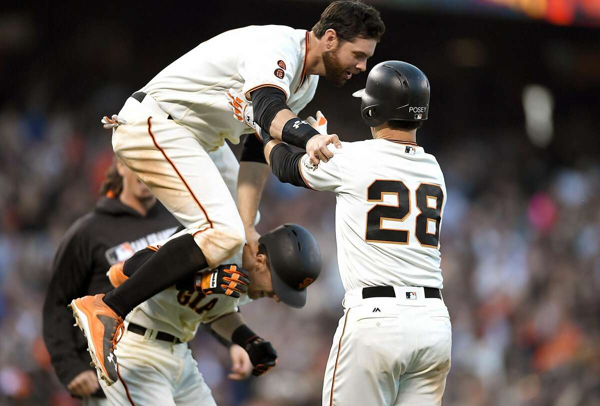 SAN FRANCISCO, CA - JUNE 11: Brandon Belt #9 of the San Francisco Giants leaps over teammate Matt Duffy #5 to celebrate with Buster Posey #28 after Posey hit a walk-off rbi single to defeat the Los Angeles Dodgers 5-4 in the bottom of the tenth inning at AT&T Park on June 11, 2016 in San Francisco, California. (Photo by Thearon W. Henderson/Getty Images)