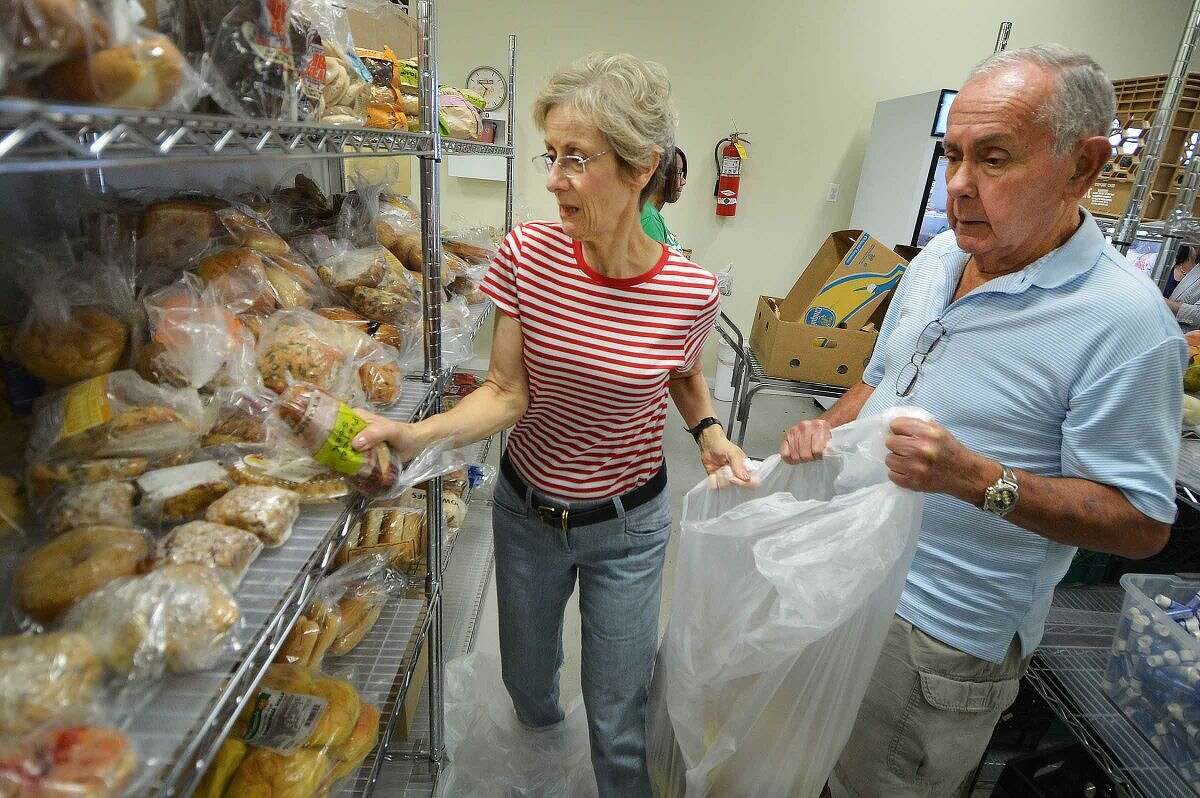 Hour Photo/Alex von Kleydorff Volunteers Nancy Hanze and Ira Miller stock the shelves with donated bread and rolls from the Community Pantries program at Person to Person.