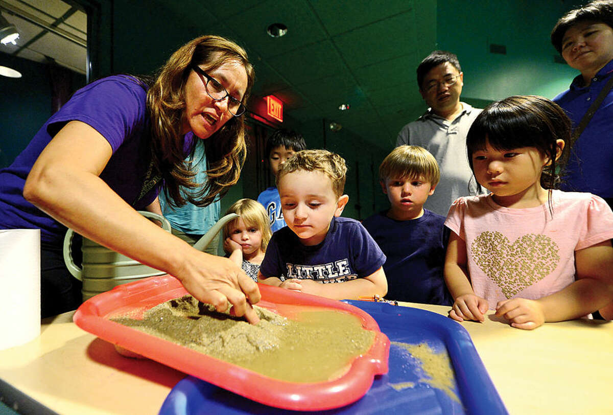 Hour photo / Erik Trautmann Mateo Cordero, 3, watches as Stepping Stones Children's Museum educator Milen Bedon demonstrates how the Grand Canyon was created through the process of erosion during the Around the World: Creative Kids workshop, Grand Canyon, at the Museum Saturday. The children also learned how to identify the different layers of rock through a sand layering craft.