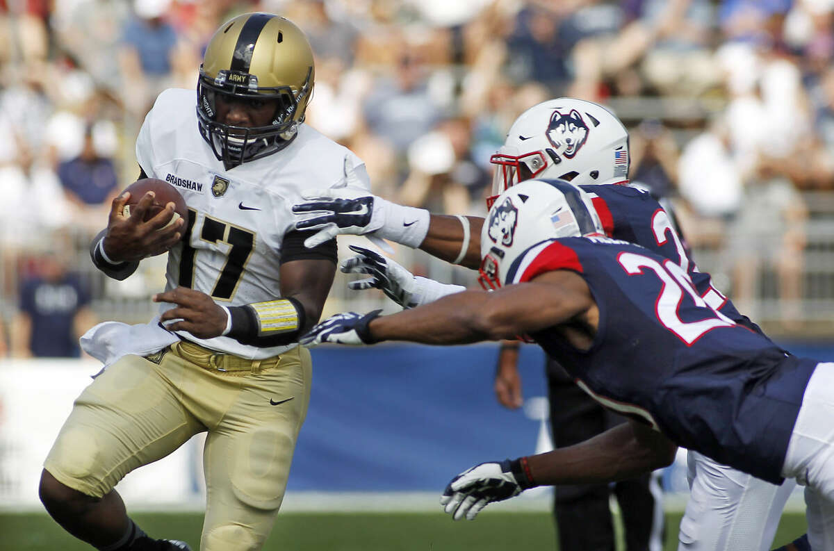 Connecticut safety Andrew Adams, rear right and Obi Melifonwu (20) tackle Army quarterback Ahmad Bradshaw (17) during the first quarter of an NCAA college football game at Rentschler Field, Saturday, Sept. 12, 2015, in East Hartford, Conn. (AP Photo/Stew Milne)