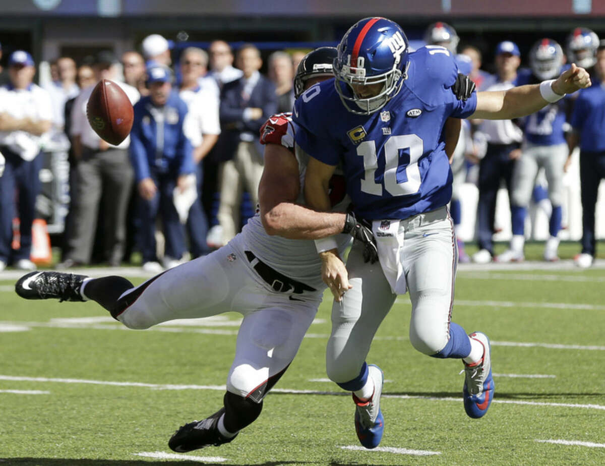 New York Giants quarterback Eli Manning, front, fumbles the ball as Atlanta Falcons outside linebacker Kroy Biermann makes the hit during the second half of an NFL football game, Sunday, Sept. 20, 2015, in East Rutherford, N.J. (AP Photo/Seth Wenig)
