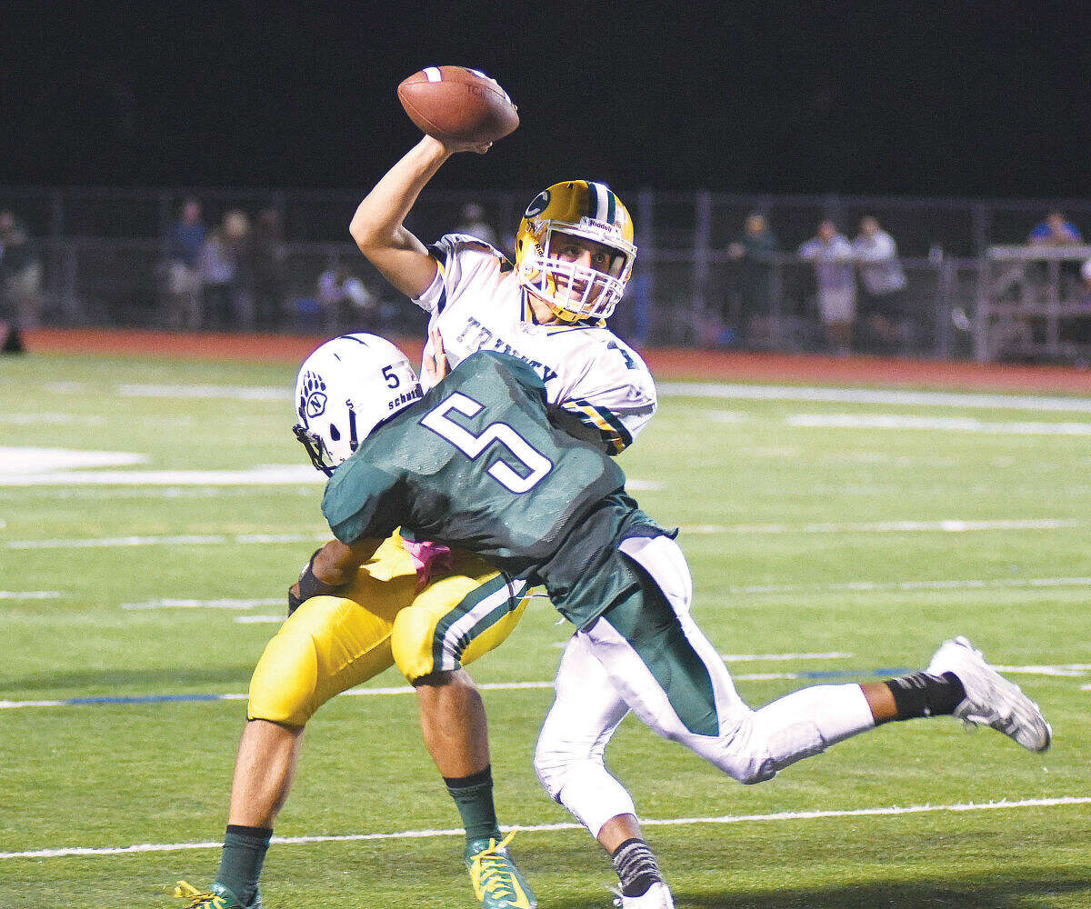 Hour photo/John Nash - Norwalk's Amyr Rivera (5) looks to bring down Trinity Catholic quarterback Anthony Lombardi during the first half of Friday night's FCIAC football game in Norwalk.