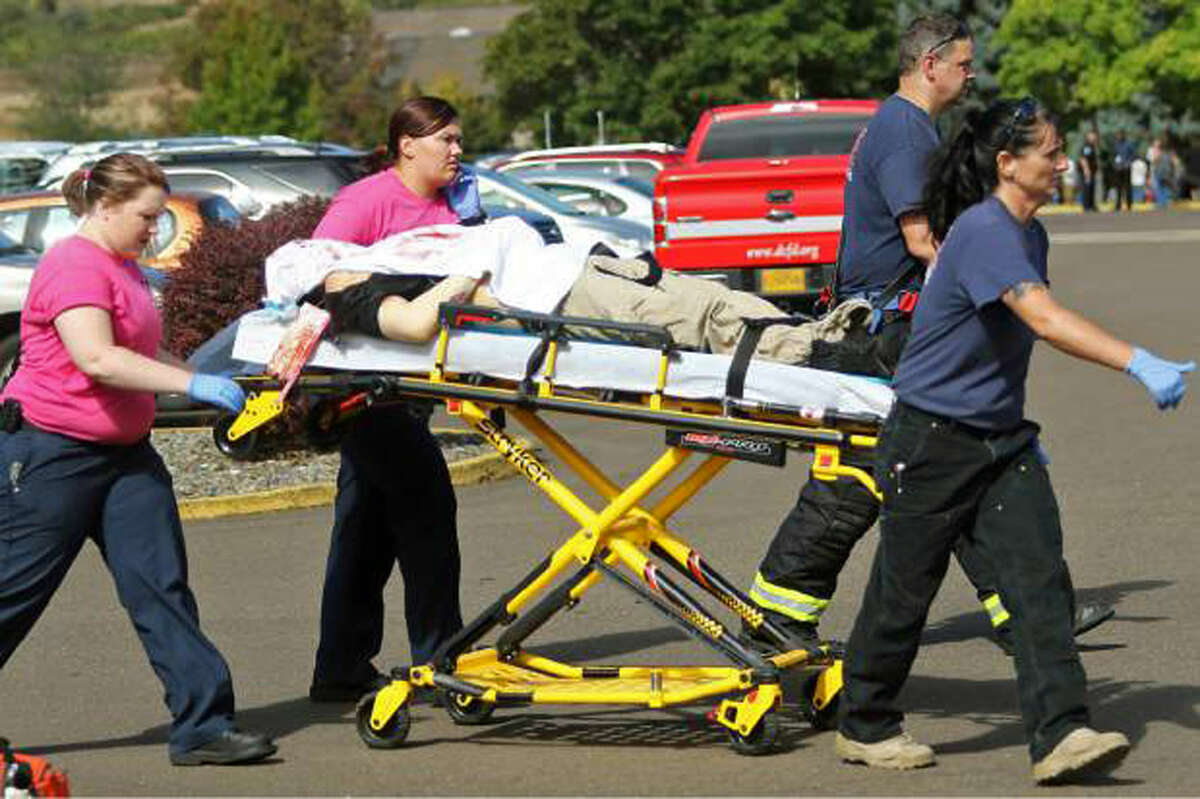 Authorities carry a shooting victim away from the scene after a gunman opened fire at Umpqua Community College in Roseburg, Ore., Thursday, Oct. 1, 2015. (Mike Sullivan/Roseburg News-Review via AP)