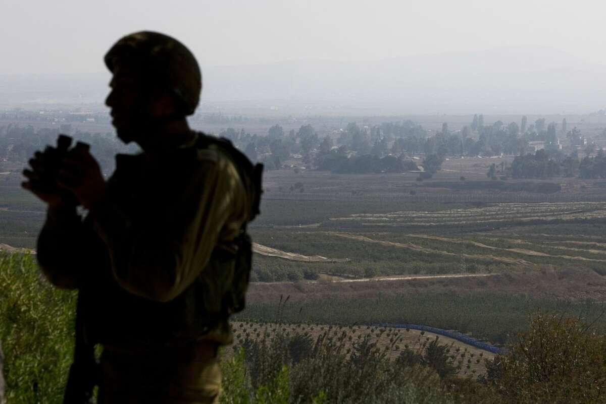 An Israeli soldier observes Syria's Quneitra province at an observation point on Mount Bental in the Israeli-controlled Golan Heights, overlooking the border with Syria, Monday, Sept. 1, 2014. (AP Photo/Sebastian Scheiner)