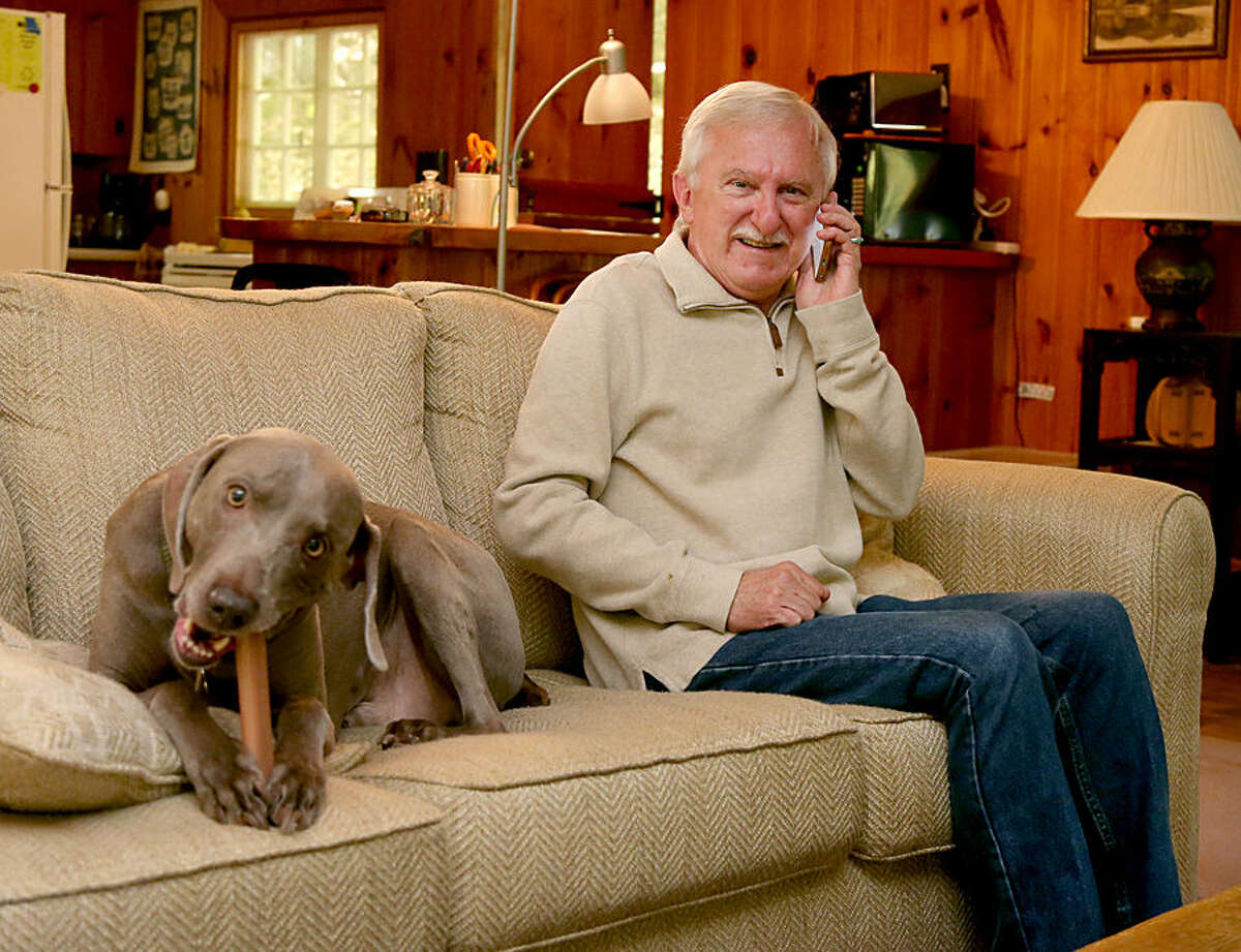 Paul Modrich takes a phone call as he sits on the couch with his dog Dover at his vacation home in Rumney, N.H., Wednesday, Oct. 7, 2015. Modrich, an investigator at Howard Hughes Medical Institute and professor at Duke University School of Medicine in Durham, N.C., is one of three scientists who won the Nobel Prize in chemistry on Wednesday for showing how cells repair damaged DNA, work that has inspired the development of new cancer treatments. (AP Photo/Mary Schwalm)