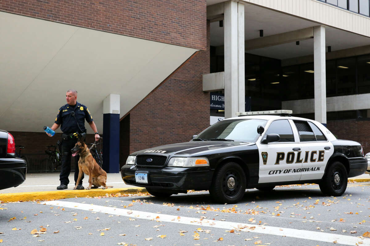 Hour photo/Chris Palermo Sgt. Reda of the Norwalk Police Departments holds his K-9 unit outside of Wilton High School during the illegal drug search Friday morning.