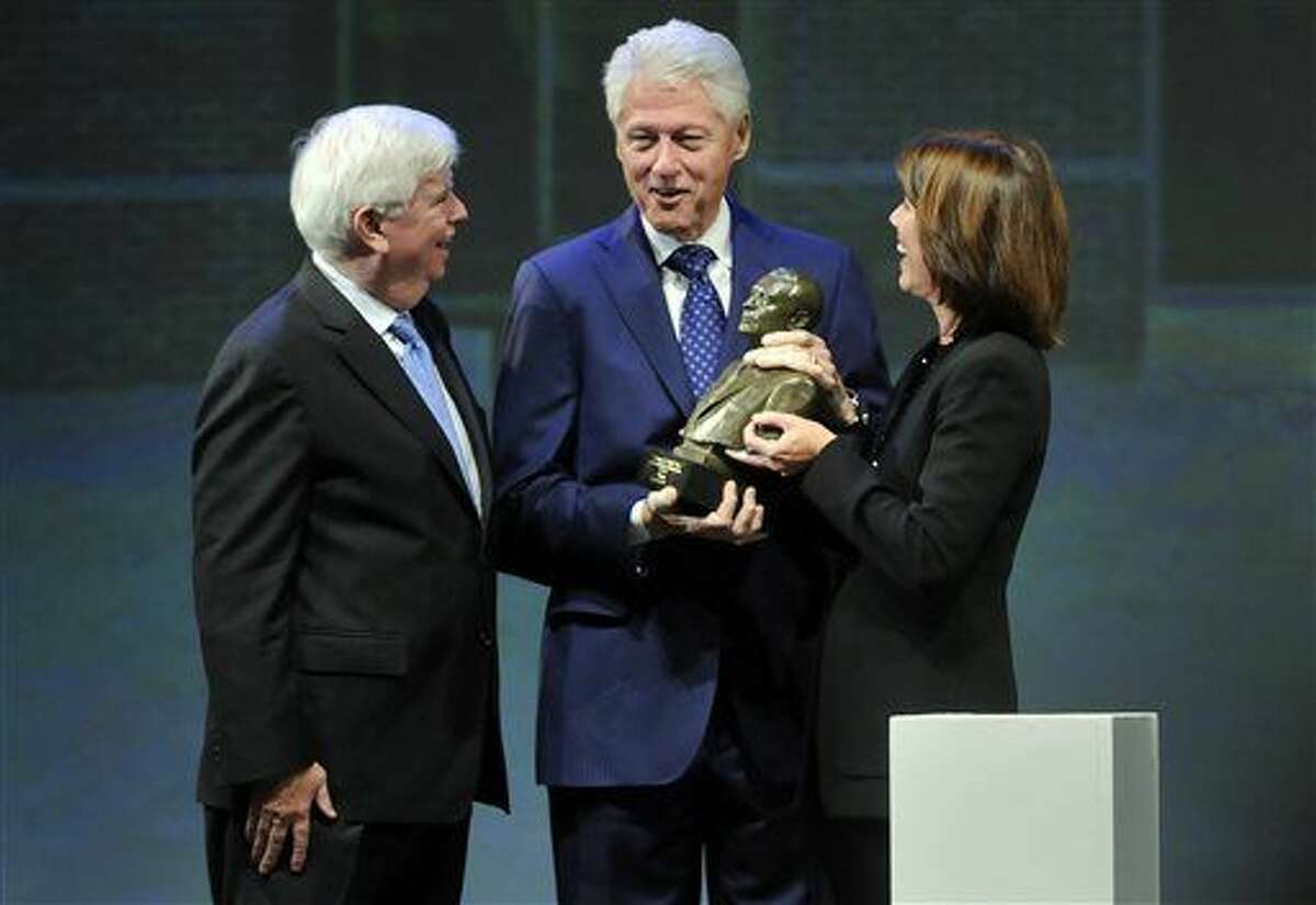 Former President Bill Clinton, center, accepts the Thomas J. Dodd Prize in International Justice and Human Rights from Helena Foulkes, right, acting chair, national advisory board of the Thomas J. Dodd Research Center, while former Connecticut Sen. Chris Dodd left, applauds during a ceremony at the Jorgensen Auditorium on the UConn campus Thursday evening, Oct. 15, 2015, in Stoors, Conn. Clinton was a co-recipient of the award along with African human rights group Tostan. (Cloe Poisson/Hartford Courant via AP) MANDATORY CREDIT