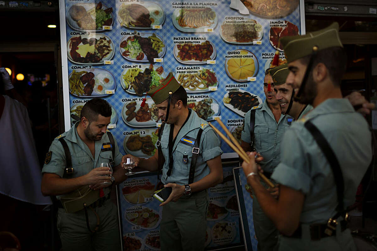 Members of La Legion, an elite unit of the Spanish Army, toast in a bar before a military parade as they celebrate a holiday known as 'Dia de la Hispanidad' or Spain's Hispanic Day in Madrid, Spain, Monday, Oct. 12, 2015. King Felipe has presided over a military parade celebrating Spain's National Day which 3,400 soldiers in crisp uniforms marched in central Madrid while armed forces aircraft performed a fly-past leaving trails of red and yellow smoke representing the Spanish flag. (AP Photo/Daniel Ochoa de Olza)