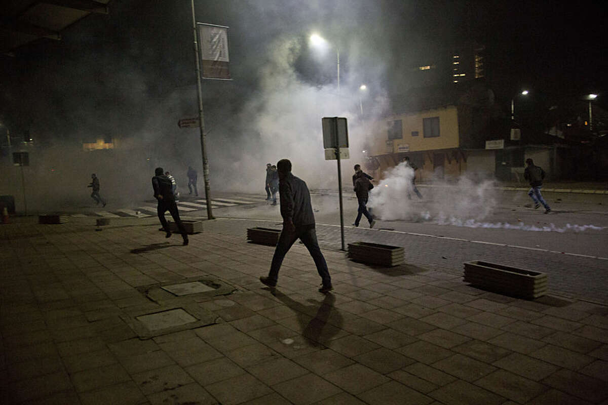 Protester run from tear gas in Kosovo capital Pristina as clashes broke out after the arrest of a prominent opposition politician Albin Kurti on Monday, Oct. 12, 2015. The main opposition parties have been protesting government’s recent EU-sponsored deal with authorities in Serbia that give Kosovo’s Serb minority greater rights in areas where they live. Albin Kurti, who is a leader of the nationalist Vetvendosje movement, set off a teargas canister inside Kosovo’s Parliament in an attempt to halt the proceedings. (AP Photo/Visar Kryeziu)
