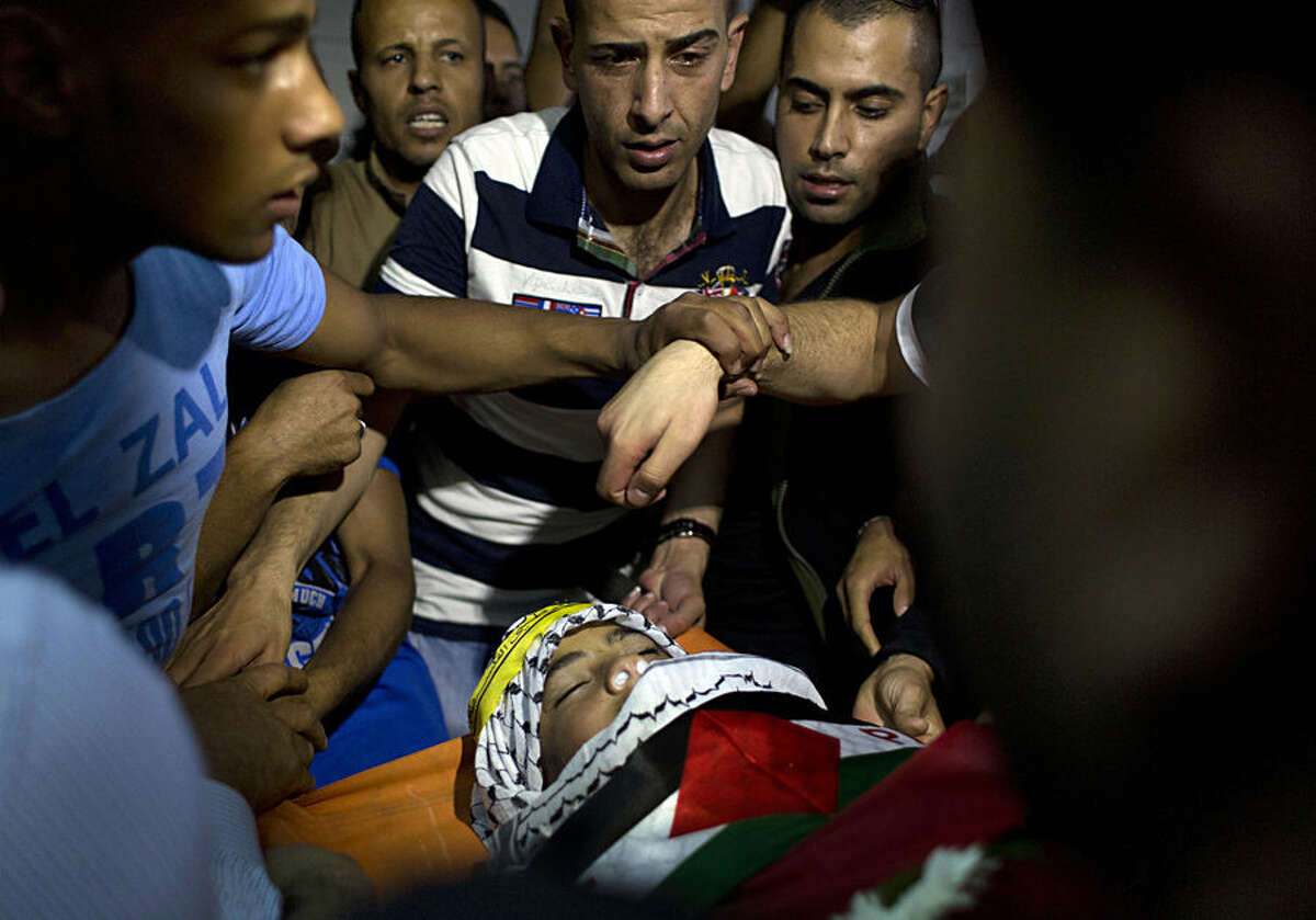 Mourners take a last at look the body of Palestinian teenager Ahmad Sharaka, 13, who was shot dead by Israeli military forces during clashes at a checkpoint near Ramallah on Sunday, at the family house during his funeral in the Palestinian West Bank refugee camp of Jalazoun, Ramallah, Monday, Oct. 12, 2015. On Sunday, Ramallah Government Hospital director Ahmed Bitawi said Ahmad Sharaka was shot dead by three live bullets to the head, neck and chest. The Israeli military had no immediate comment. (AP Photo/Nasser Nasser)