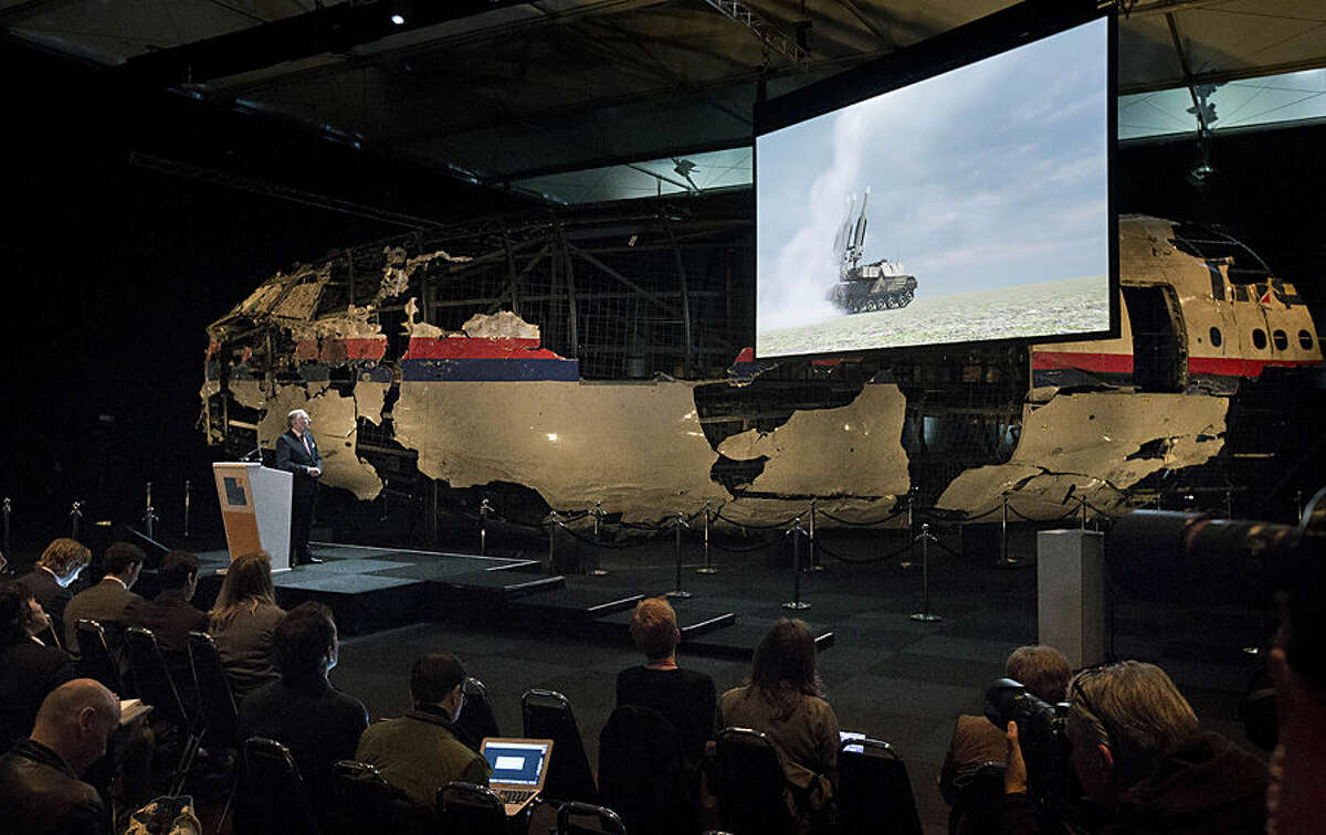 A video show the launch of a BUK missile, while a part of the reconstructed forward section of the fuselage is displayed behind, as Tjibbe Joustra, left, head of the Dutch Safety Board presents the board’s final report into what caused Malaysia Airlines Flight 17 to break up high over Eastern Ukraine last year, killing all 298 people on board, during a press conference in Gilze-Rijen, central Netherlands, Tuesday, Oct. 13, 2015. (AP Photo/Peter Dejong)