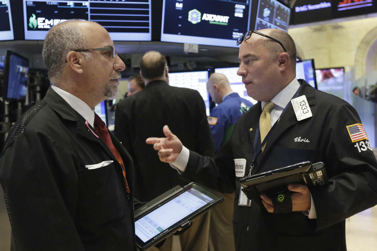 Traders John Liotti, left, and Christopher Morie confer on the floor of the New York Stock Exchange, Monday, Oct. 12, 2015. Stocks are little changed in early trading as traders look ahead to the start of corporate earnings season. (AP Photo/Richard Drew)