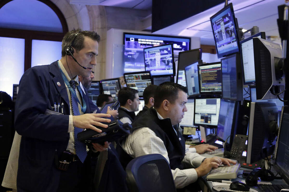 Trader Gregory Rowe, left, works with colleagues in their booth on the floor of the New York Stock Exchange, Monday, Oct. 12, 2015. Stocks are little changed in early trading as traders look ahead to the start of corporate earnings season. (AP Photo/Richard Drew)