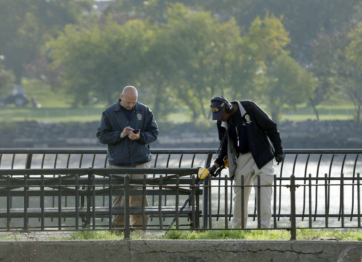 Police officers, including one with a metal detector, work at the scene of a fatal police shooting in New York, Wednesday, Oct. 21, 2015. Officer Randolph Holder, responding to a report of shots fired, was killed during a gunfight and chase involving a stolen bicycle. A suspect in his slaying is in custody, police said Wednesday. (AP Photo/Seth Wenig)