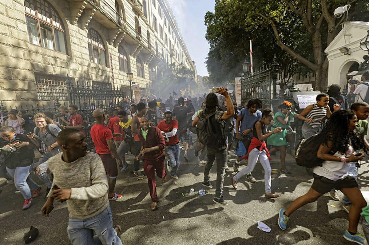 Protesting university students flee as police fire stun grenades outside Parliament in Cape Town, South Africa, Wednesday Oct. 21, 2015. The protests are part of a wave of nationwide protests that have shut down many South Africa universities, which say they are struggling with higher operational costs as well as inadequate state subsidies. (AP Photo)