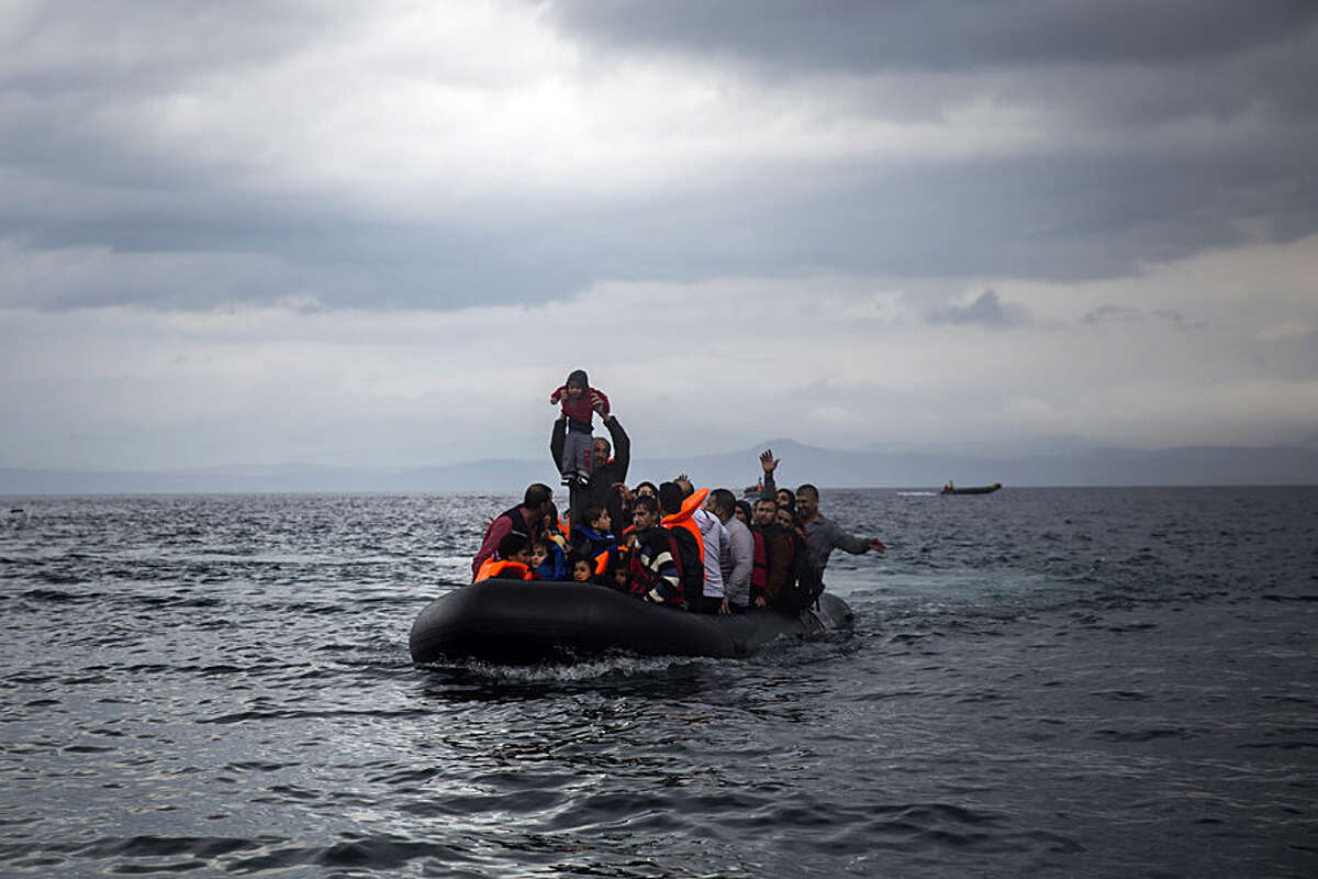 A man holds up a young girl as they arrive with other migrants on a dinghy from the Turkish coast to Skala Sikaminias village on the northeastern Greek island of Lesbos, Wednesday, Oct. 21, 2015. Greece is the main entry point for those fleeing violence at home and seeking a better life in the European Union. More than 500,000 people have arrived so far this year on Greece's eastern islands, paying smugglers to ferry them across from nearby Turkey. (AP Photo/Santi Palacios)