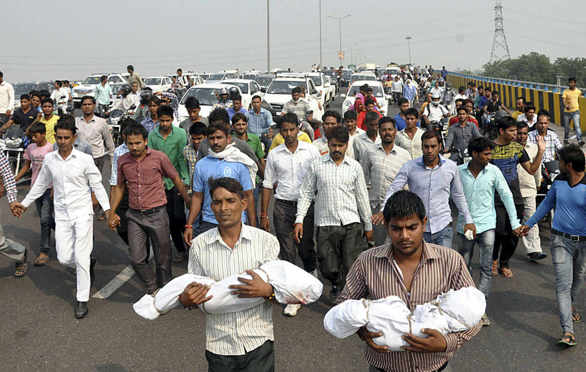Relatives carry the bodies of a baby and a toddler killed in a house fire allegedly set by their family's upper caste neighbors, as angry residents block a highway in Faridabad near New Delhi, India, Wednesday, Oct.21, 2015. The 2½-year-old and 9-month old were sleeping when the attackers poured gasoline and set the fire in Sunpedh village Monday night. The residents blocked the key highway near the Indian capital to demand the attackers be arrested.(AP Photo/ Vijay Kumar)