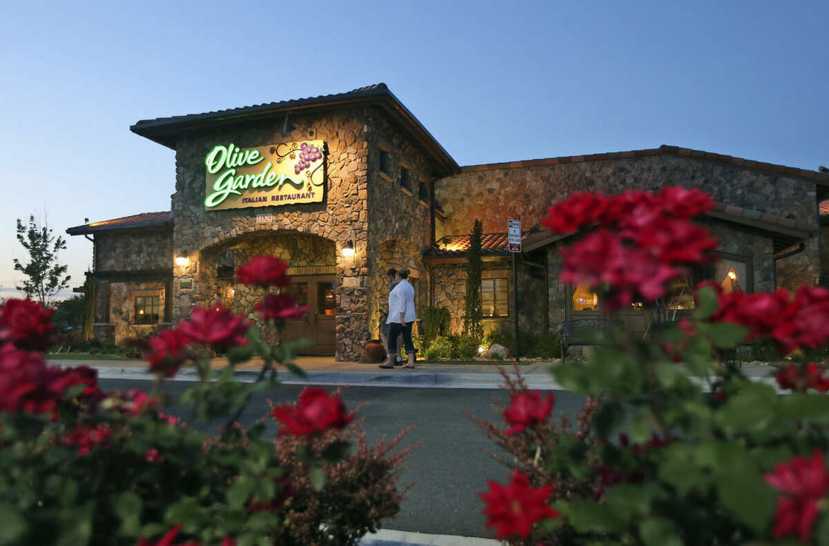 In this May 22, 2014 photo, patrons enter an Olive Garden Restaurant in Short Pump, Va. Olive Garden is hurting itself by piling on too many breadsticks, according to an investor that's disputing how the restaurant chain is run. (AP Photo/Steve Helber)