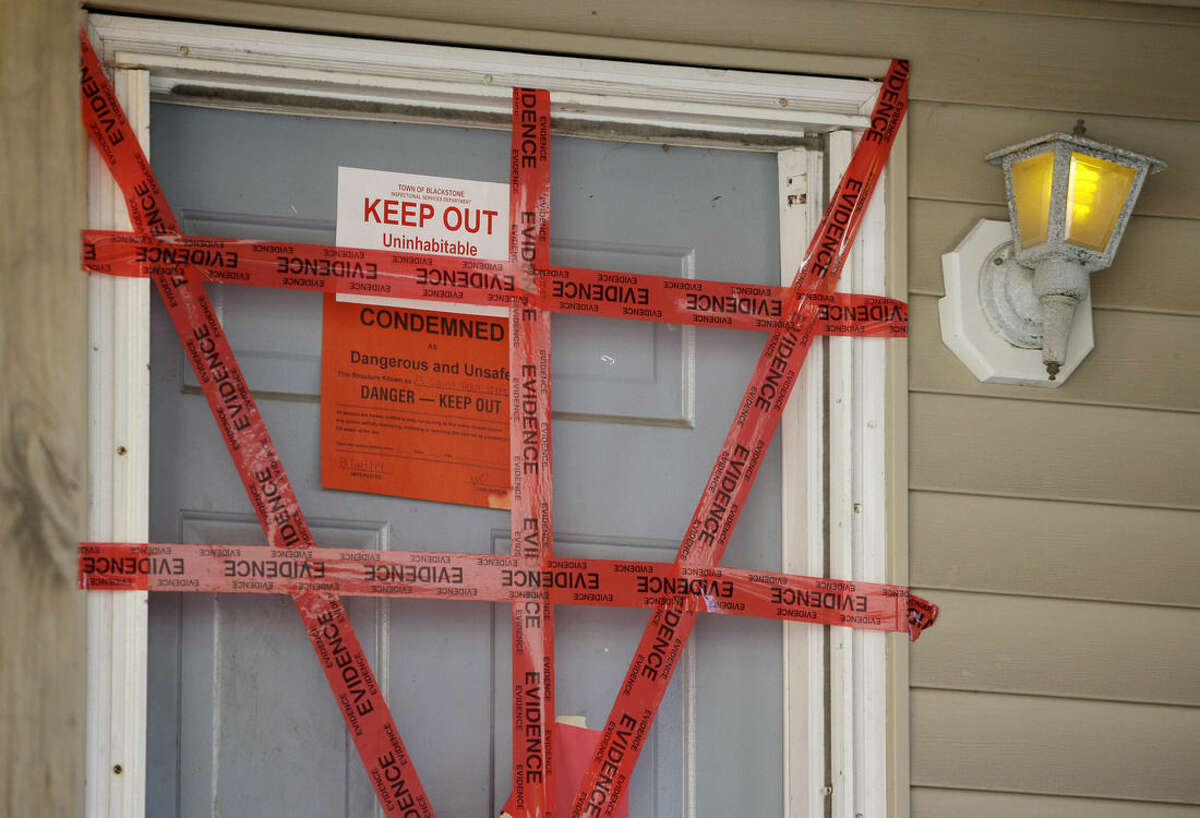 Both "condemned" and "keep our" signs are attached behind police tape to the front door of a house where a Massachusetts prosecutor said the bodies of three infants were found Thursday in Blackstone, Mass., Friday, Sept. 12, 2014. Erika Murray, 31, was arrested Thursday night on charges including fetal death concealment, witness intimidation and permitting substantial injury to a child. Not guilty pleas were entered Friday on her behalf. (AP Photo/Stephan Savoia)