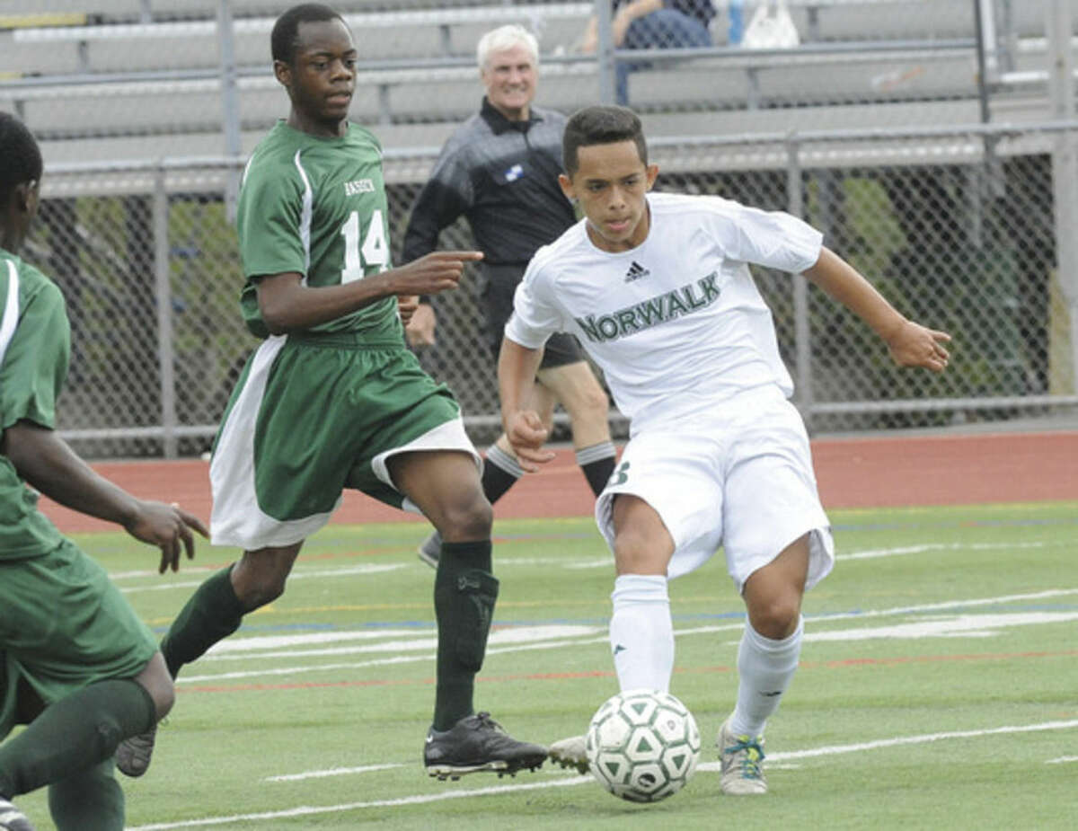 Hour photo/Matthew Vinci Norwalk's Miguel Argueta, right, evades a challenge from Bassick's Todd Mhlange during Tuesday's game.