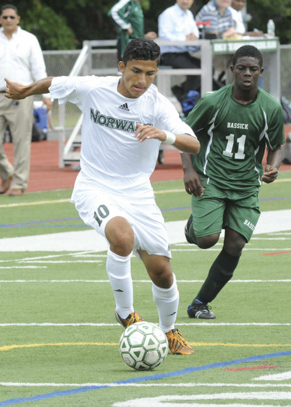 Hour photo/Matthew Vinci Norwalk's Patrick Barrantes, front, dribbles past Bassick's Simon McIntyre during Tuesday's game at Norwalk High. Barrantes scored three first half goals to help the Bears to their first win of the season.
