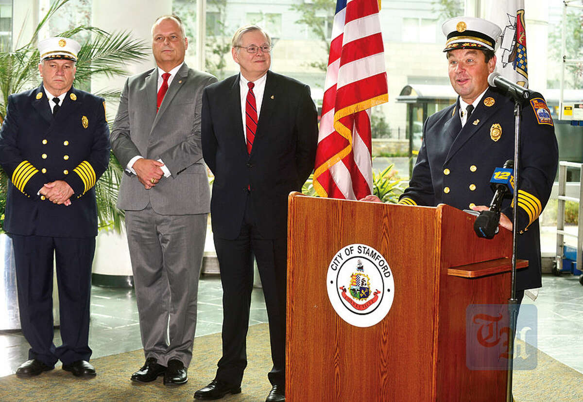 Hour photo / Erik Trautmann Assistant Fire Chief, Trevor Roach, speaks while Director of Public Safety, Ted Jankowski, and Mayor David Martin, look on, during a press conference at the Stamford Government Center Wednesday announcing his appointment to Chief of the Stamford Fire Department after the retirement of Chief Peter Brown, left, in December.