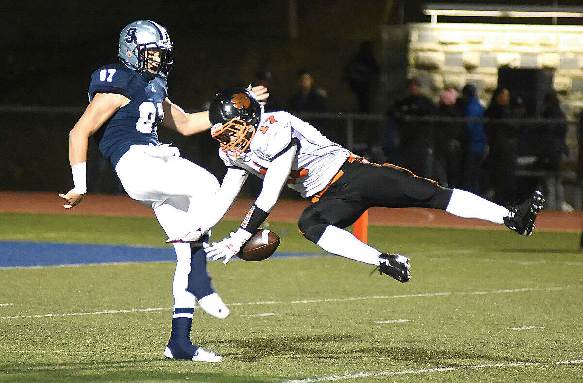 Hour photo/John Nash - Staples punter Ryan Fitton, left, has hit kick blocked by Ridgefield's Dante Cobelli during the first quarter of Friday night's FCIAC football game in Westport. Ridgefield turned the short field into a touchdown en route to a 31-27 win over the previously undefeated Wreckers.