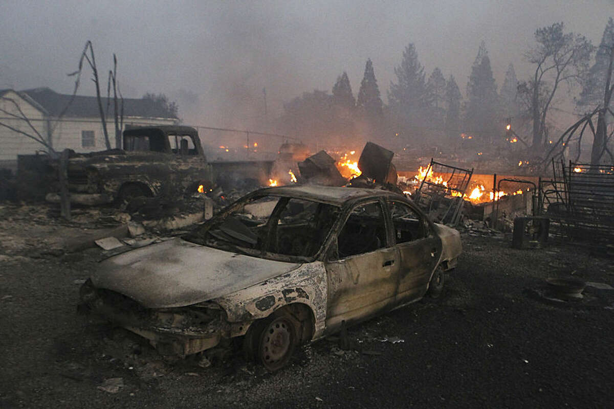 In this Monday, Sept. 15, 2014 photo, vehicles and homes are destroyed in Weed, Calif. where a wind-driven wildfire raced through the hillside neighborhood and forced more than 1,000 people to flee the small town near the Oregon border. The fast-moving blaze, which began Monday, was among nearly a dozen wildfires burning in California that have been exacerbated by the state's third straight year of drought. (AP Photo/The Record Searchlight, Greg Barnette)