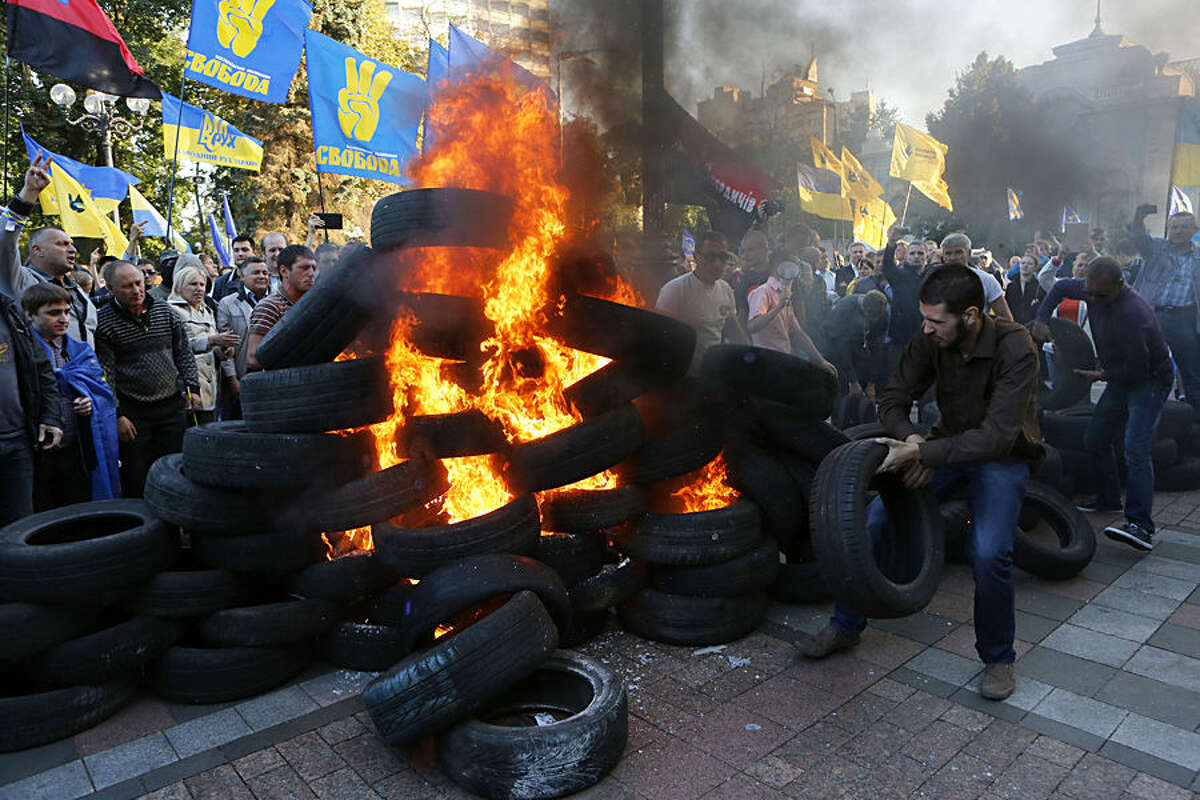 Ukrainian protesters burn tires outside the Ukrainian parliament in Kiev, Ukraine Tuesday, Sept. 16, 2014. The demonstrators rallied in support of a bill that would ban those who cooperated with the old pro-Russian government from running for public office. (AP Photo/Sergei Chuzavkov)