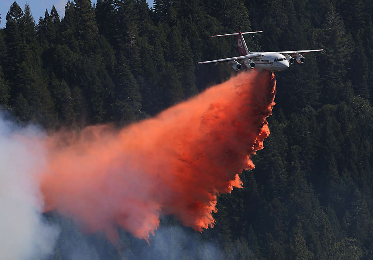 A jet aerial tanker drops its load of fire retardant on a fire near Pollack Pines, Calif., Monday, Sept. 15, 2014. The fire, which started Sunday has consumed more than 3,000 acres and forced the evacuation of dozens of homes. (AP Photo/Rich Pedroncelli)
