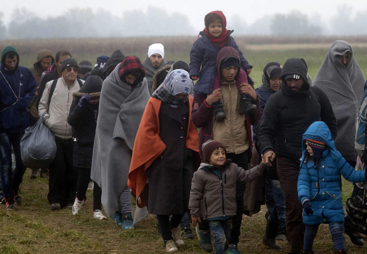 Migrants move through a field after crossing from Croatia, in Rigonce, Slovenia, Sunday, Oct. 25, 2015. Thousands of people are trying to reach central and northern Europe via the Balkans, but often have to wait for days in mud and rain at the Serbian, Croatian and Slovenian borders. (AP Photo/Darko Bandic)