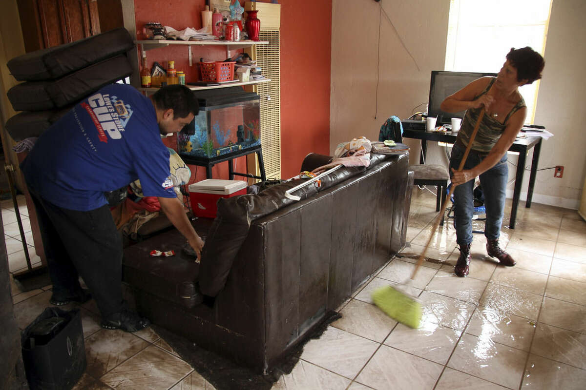 Elena Santellan sweeps water while Pedro Hernandez moves a sofa in El Paso, Texas, Thursday, Sept. 18, 2014. Heavy rains caused street flooding and other incidents in Far West Texas and Southeastern New Mexico. (AP Photo/Juan Carlos Llorca)