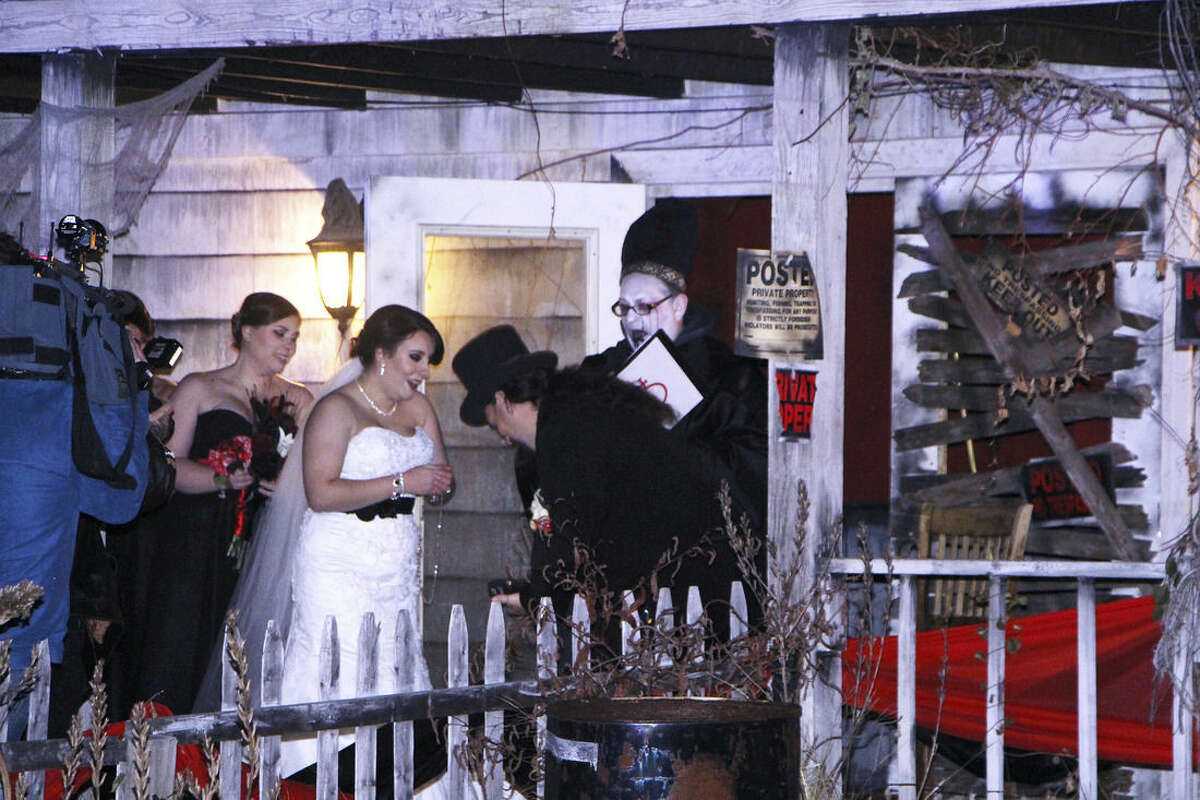 In this photo provided by Spooky World Presents Nightmare New England, Melissa Cote and Tom Cowen, who both work at Spooky World Presents Nightmare New England in Litchfield, N.H., were married the night of Monday, Oct. 26, 2015, in front of the attraction's haunted house. During the ceremony, the justice of the peace encouraged them to "haunt and howl at the moon together as long as you shall live," and "to have and to hold from this night on, in madness and in haunting fun." (Spooky World Presents Nightmare New England via AP)