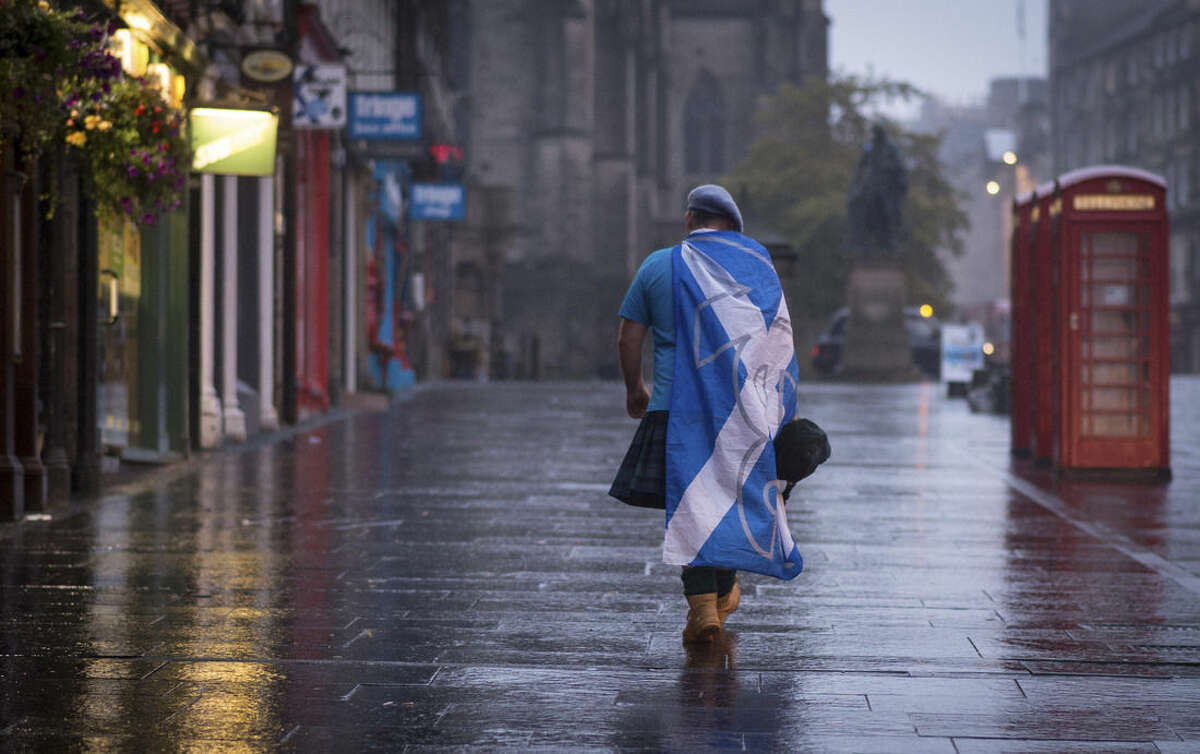 A lone YES campaign supporter walks down a street in Edinburgh after the result of the Scottish independence referendum, Scotland, Friday, Sept. 19, 2014. Scottish voters have rejected independence and decided that Scotland will remain part of the United Kingdom. The result announced early Friday was the one favored by Britain's political leaders, who had campaigned hard in recent weeks to convince Scottish voters to stay. It dashed many Scots' hopes of breaking free and building their own nation. (AP Photo/PA, Stefan Rousseau) UNITED KINGDOM OUT, NO SALES, NO ARCHIVE