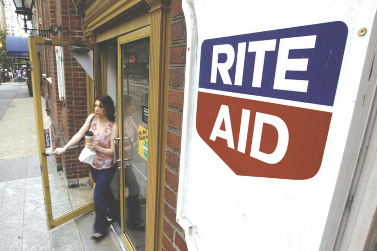 FILE- In this June 20, 2011, file photo, a woman exits a Rite Aid store, in Philadelphia. The Wall Street Journal said Walgreens Boots Alliance is in advanced talks to buy Rite Aid. Walgreens declined to comment Tuesday, Oct. 27, 2015, when contacted by The Associated Press. The deal would combine the largest and third-largest U.S. drugstore chains, based on store counts. (AP Photo/Matt Rourke, File)