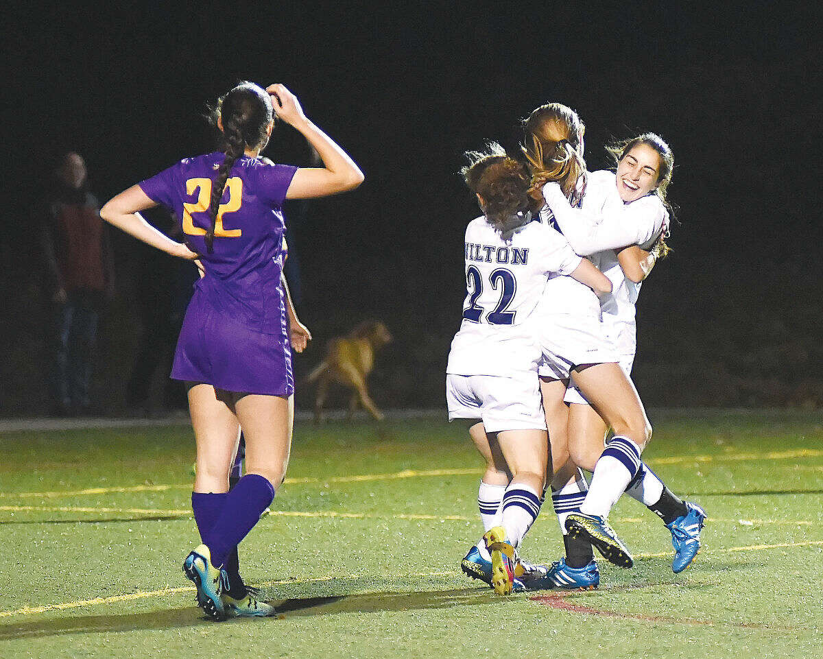 Hour photo/John Nash Wilton High’s Rebecca Hersch (22 in white) and Zoe Lash, far right, embrace teammate Ally Dejana as Westhill’s Erica Shaulson looks on after Dejana scored the only goal in the Warriors 1-0 first round state tournament win at Kristine Lilly Field on Monday. The freshman’s tally came in 10:30 left in the game, sending Wilton into the second round.