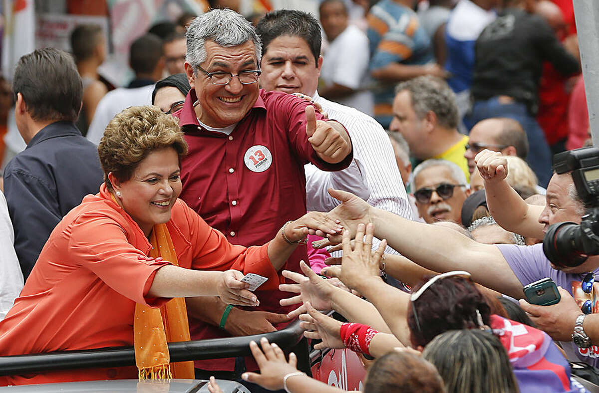 Brazil's President Dilma Rousseff, who is running for reelection with the Workers Party (PT), left, and Workers Party Sao Paulo gubernatorial candidate Alexandre Padilha, right, greet supporters at a campaign rally in Santos, Brazil, Tuesday, Sept. 30, 2014. Brazil will hold general elections on Oct. 5. (AP Photo/Andre Penner)