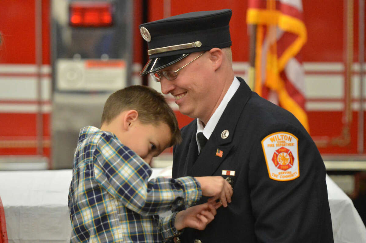 Firefighter Bill Wilson has his badge pinned on him by his 7-year-old son Jackson as he is promoted to lieutenant during a ceremony at Wilton Fire Headquarters that promoted Bill Sampson to Lieutenant and Firefighters James Blanchfield and Brian Elliott to captain.