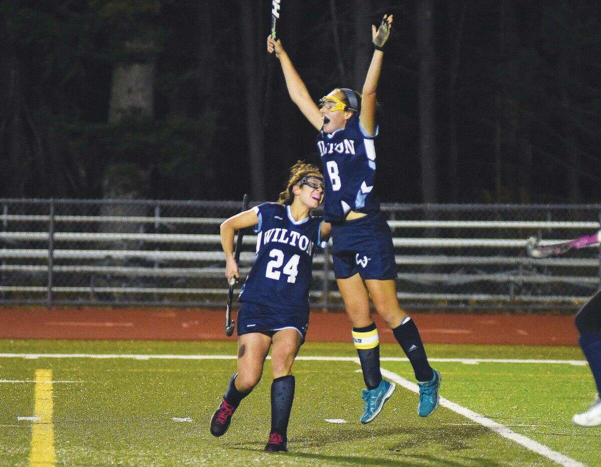 Hour photo/John Nash - Wilton's Jillian Mahon leaps into the air after scoring her team's fifth and final goal as fellow Warriors player Sophia Kaplan joins the celebration as Wilton beat Conard 5-0 in a CIAC Class L field hockey semifinal at Cheshire High School's Alumni Field on Tuesday.