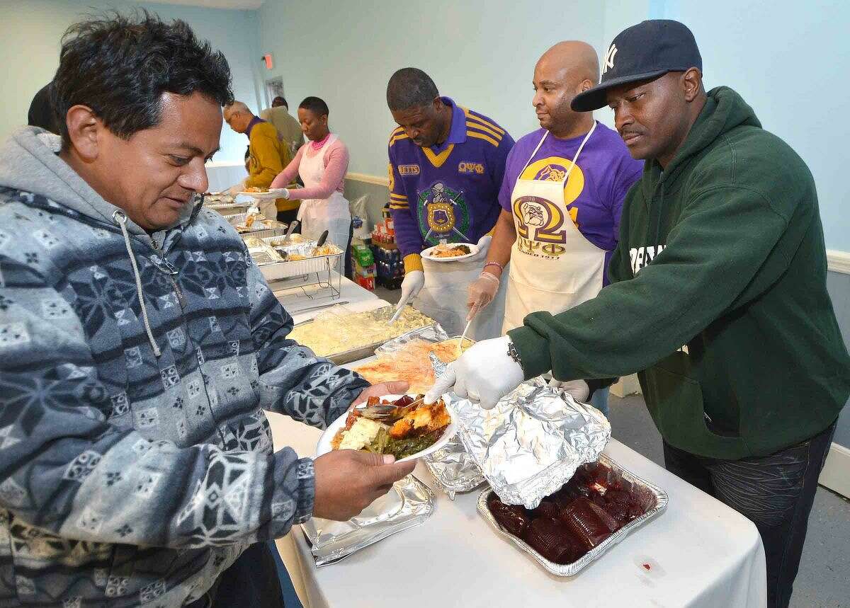Hour Photo/Alex von Kleydorff Travis Simms and members of the Fraternity Omega Psi Phi gets the cranberry sause on the plates during the Community Thanksgiving Dinner sponsored by Ernie and Martha Dumas and South Norwalk residents
