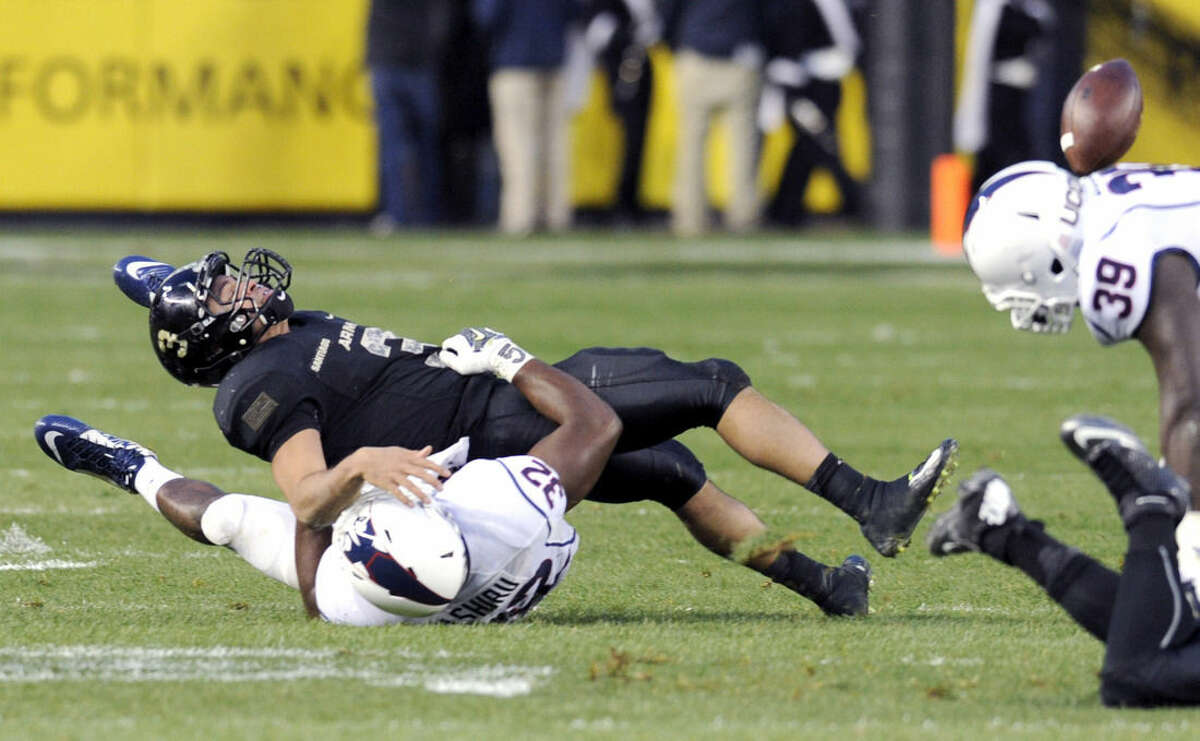 Army quarterback Angel Santiago (3) fumbles the ball as he is tackled by Comnnecticut linebacker Jefferson Ashiru (32) during the first half of an NCAA college football game against Connecticut Saturday, Nov. 8, 2014, at Yankee Stadium in New York. (AP Photo/Bill Kostroun)