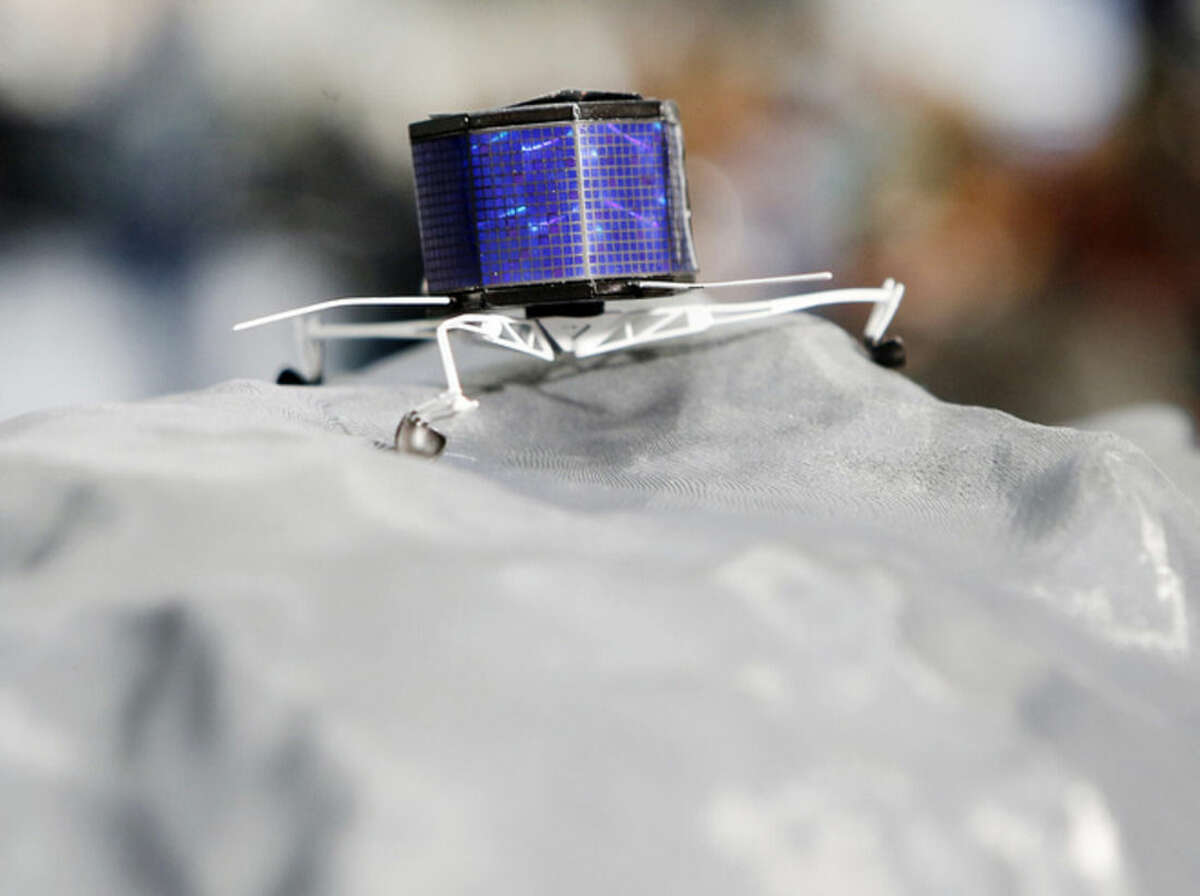 A model of Rosetta lander Philae stands on a model of comet 67P/Churyumov-Gerasimenko, at the European Space Agency ESA in Darmstadt, Germany, Wednesday, Nov.12, 2014. Europe's Rosetta space probe was launched in 2004 with the aim of studying the comet and learning more about one of the biggest questions about the origin of the universe. (AP Photo/Michael Probst)
