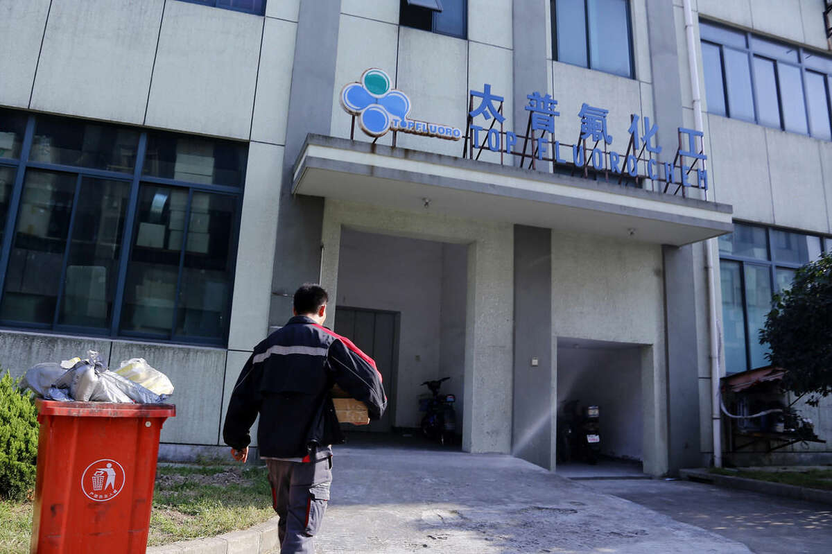 This photo taken Oct. 13, 2014 shoes a delivery man walking in front of Shanghai Top Fluoro company in Shanghai, China. Shanghai Top Fluoro is described by Tianhe as a trading company that buys as much as $100 million in high-priced chemicals from Tianhe every year. (AP Photo)