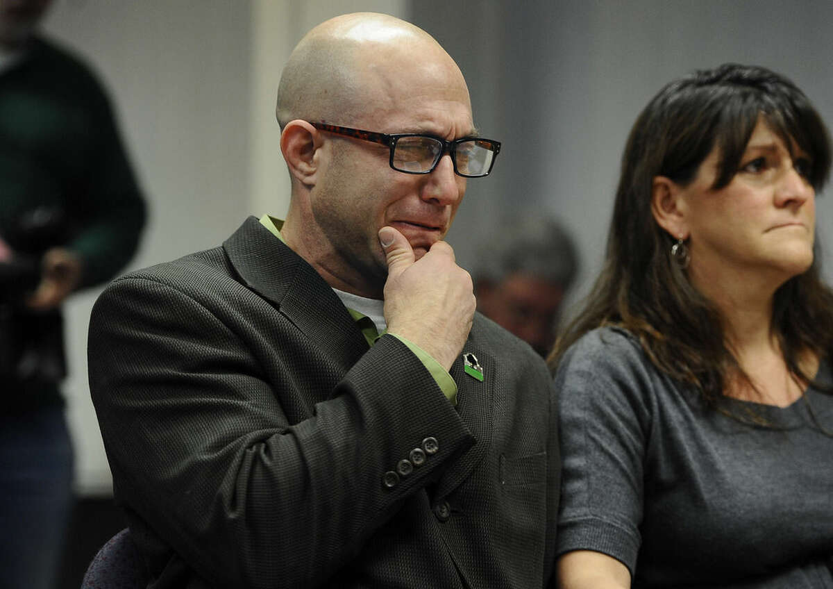 Jeremy Richman, left, weeps as he watches a video of his daughter, Sandy Hook Elementary school shooting victim Avielle Richman as wife Jennifer Hensel, right, sits beside him during a presentation to the Sandy Hook Advisory Commission, Friday, Nov. 14, 2014, in Newtown, Conn. The parents of two children killed made presentations on ways to better address mental health, school safety and gun violence prevention. (AP Photo/Jessica Hill)