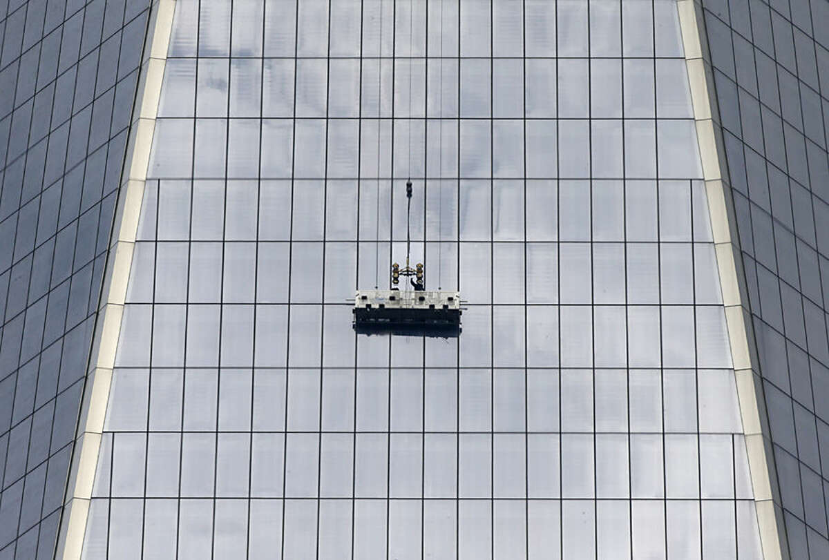Workers, using a scaffold, replace a window at 1 World Trade, Thursday, Nov. 13, 2014, in New York, the day after two window washers were rescued from a dangling scaffold by firefighters who cut through the pane to reach them. (AP Photo/Kathy Willens)