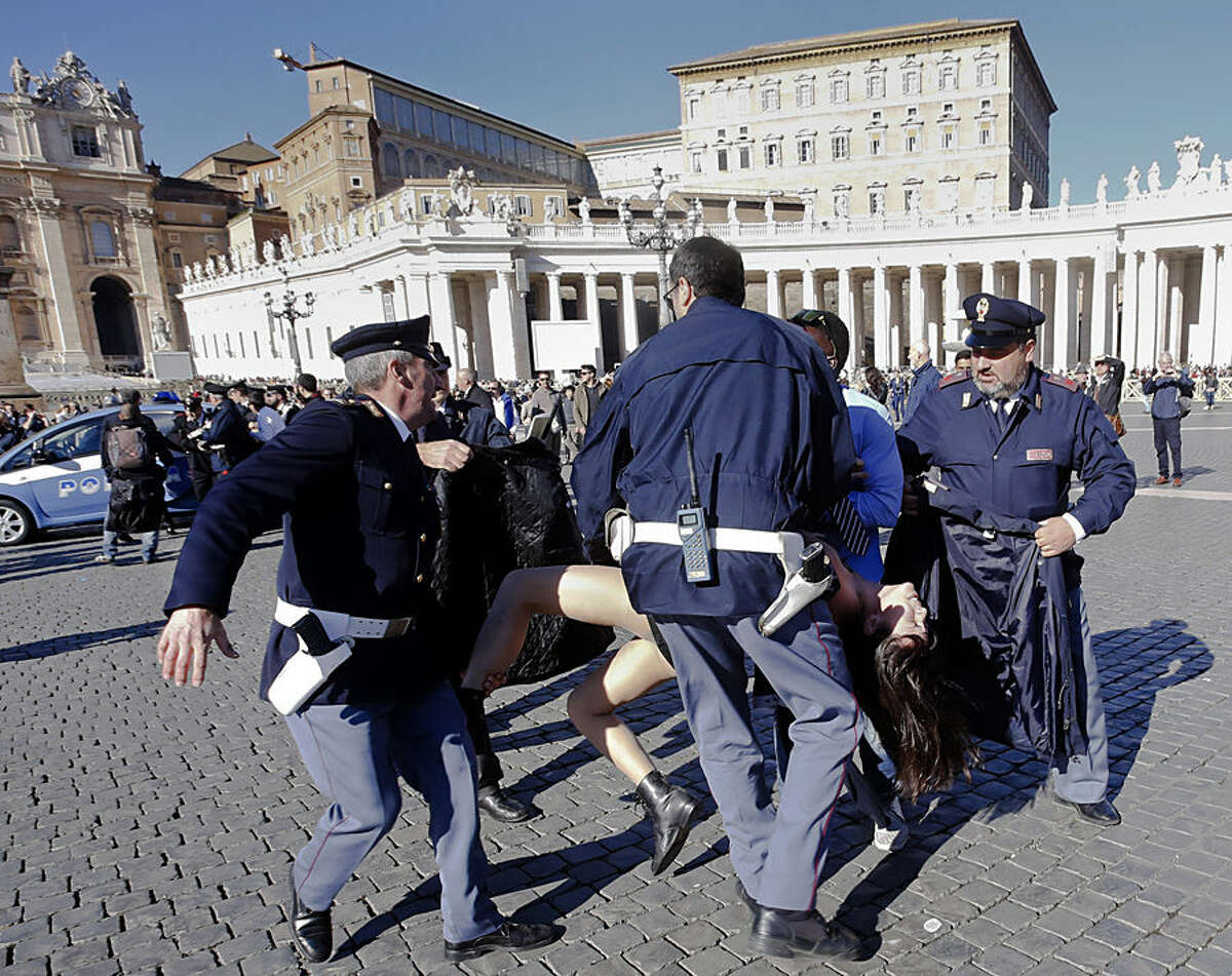 Italian police officers carry away a Femen activist during a protest in St. Peter's Square at the Vatican, Friday, Nov. 14, 2014. Members of the Ukrainian feminist group Femen staged a protest against the upcoming visit of Pope Francis at the European Parliament and Council. (AP Photo)