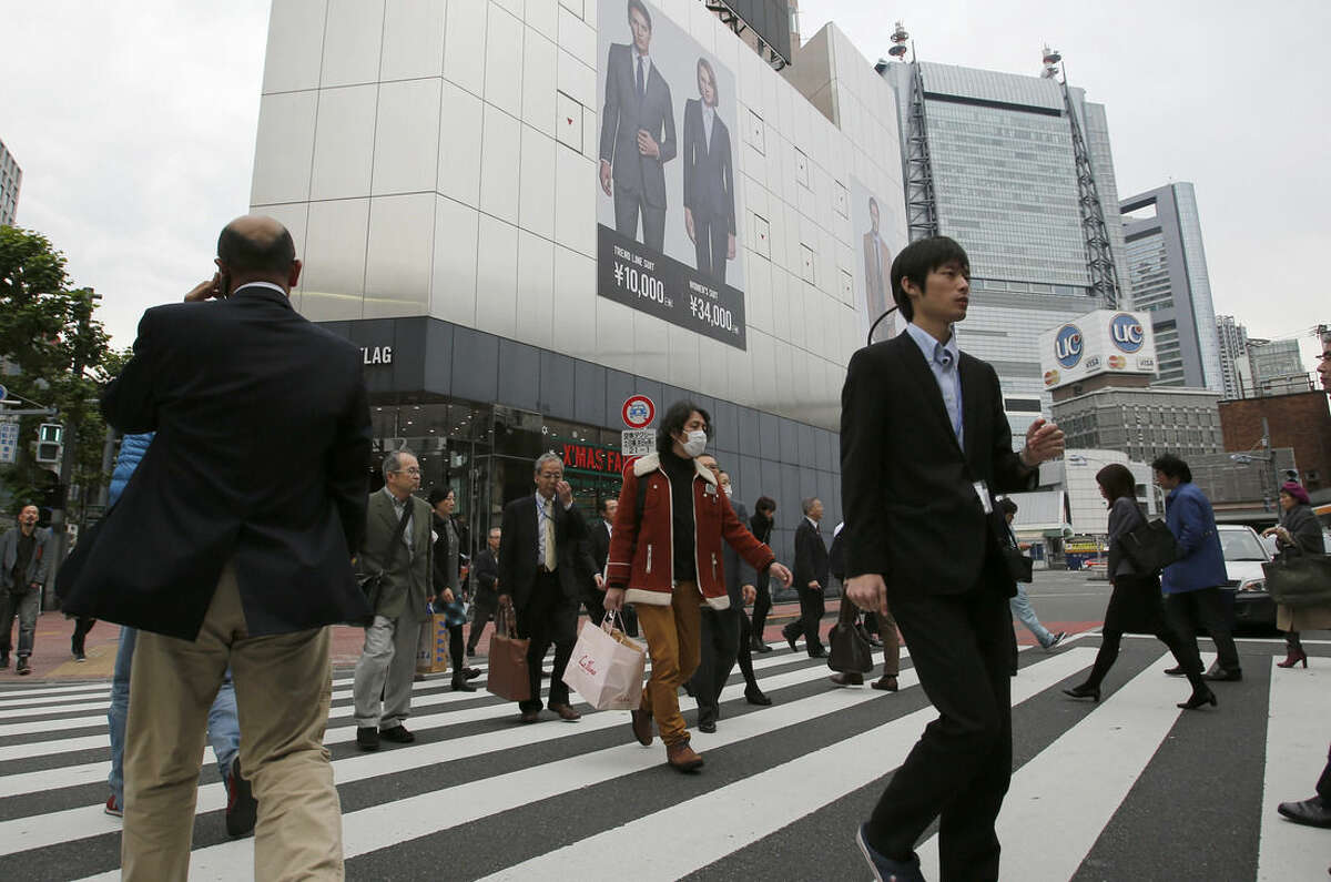 People walk on a pedestrian crossing in Tokyo Monday, Nov. 17, 2014. Japan's economy unexpectedly slid into recession as housing and business investment declined following a sales tax hike, further clouding the outlook for the global economy. (AP Photo/Shizuo Kambayashi)