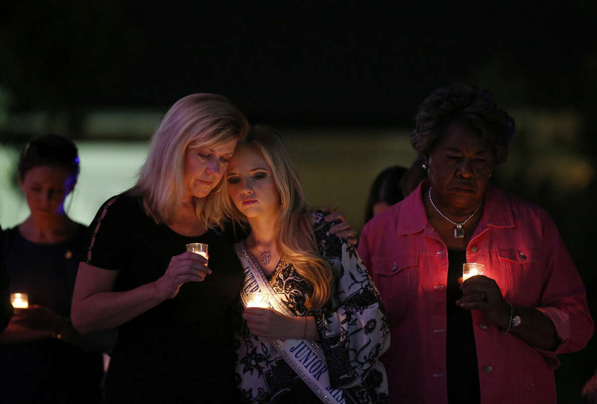 ADVANCE FOR USE MONDAY, NOV. 17, AND THEREAFTER - In this Oct. 1, 2014 photo, Elizabeth Jones, left, and her daughter Taylor Jones, 19, right, attend a candlelight vigil to support Domestic Violence Awareness Month in Montgomery, Ala. Taylor Jones said she was a victim of domestic violence when she was 15-years-old and now stands against domestic violence as an International Junior Miss Teen. Jones says that she started an organization called TIARA Charities (Teens In-action Against Relationship Abuse) in hopes to bring abuse awareness to her community. (AP Photo/Brynn Anderson)