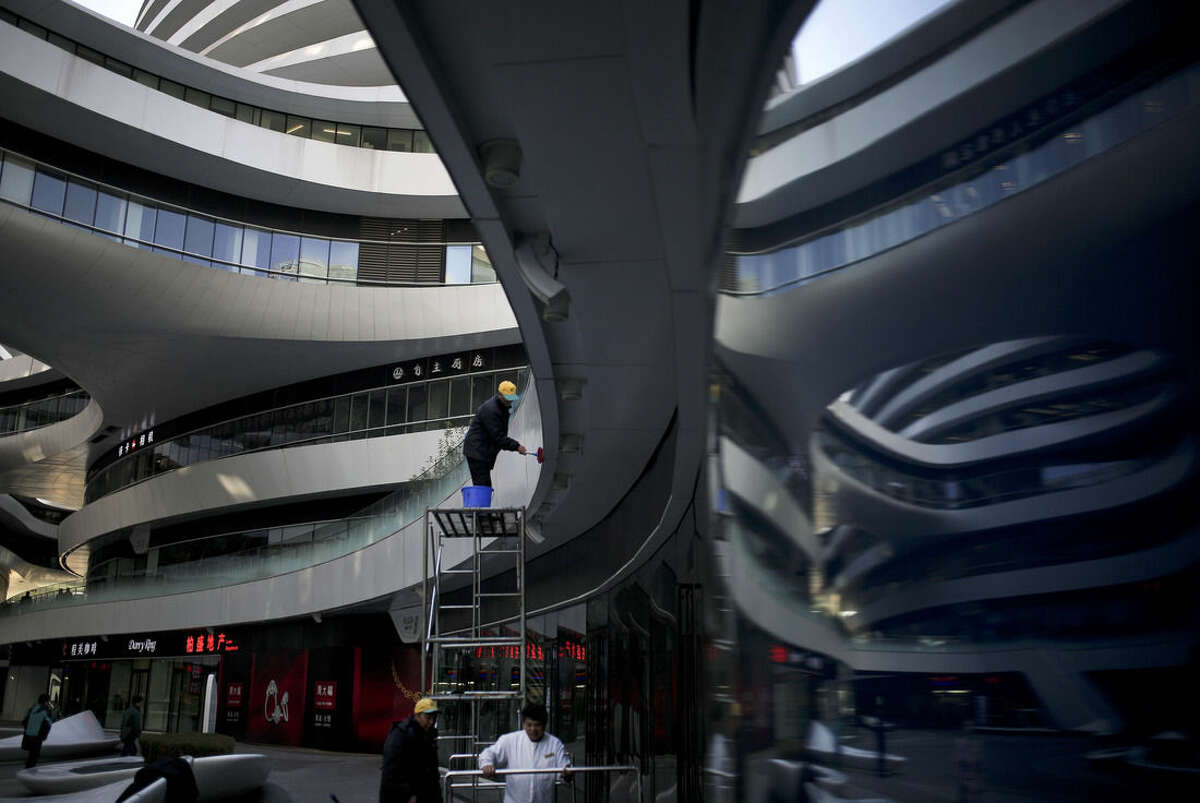 A cleaner stands on a platform wipes on the Galaxy Soho, a newly built commercial building in Beijing, China Monday, Nov. 17, 2014. Under pressure to jolt the lethargic world economy back to life, leaders of G-20 nations on Sunday finalized a plan to boost global GDP by more than $2 trillion over five years. (AP Photo/Andy Wong)