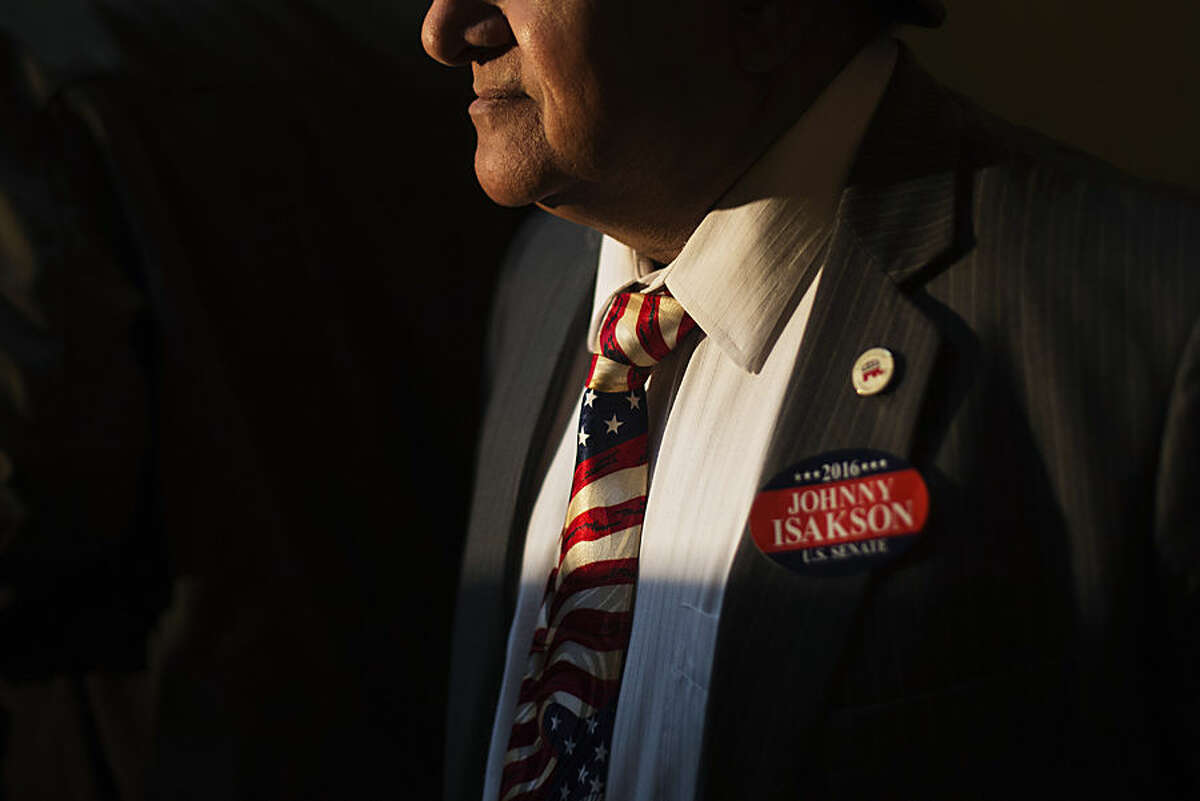 Former Republican Congressional candidate Shahid Malik wears a tie decorated like the American flag and a sticker supporting Sen. Johnny Isakson, R-Ga., at a news conference where Isakson announced his re-election bid for the 2016 campaign at the state Capitol, Monday, Nov. 17, 2014, in Atlanta. The Republican, who'll be seeking his third term, told about 200 supporters Monday that he wants to keep fighting to build up Georgia's infrastructure, pass a balanced budget amendment and reduce federal spending. Gov. Nathan Deal praised Isakson as a "stable conservative leader." (AP Photo/David Goldman)
